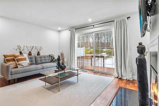 living area with visible vents, baseboards, recessed lighting, wood finished floors, and a glass covered fireplace