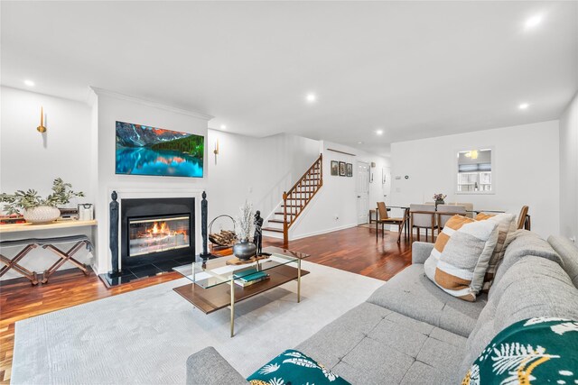 living room with a glass covered fireplace, stairway, recessed lighting, and wood finished floors