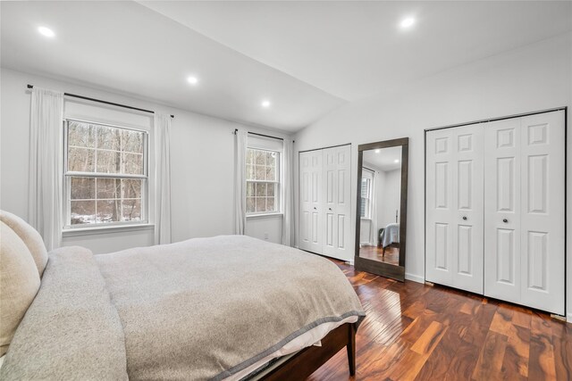 bedroom with lofted ceiling, recessed lighting, dark wood-style floors, and two closets