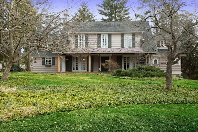 view of front of property with french doors, covered porch, and a front lawn