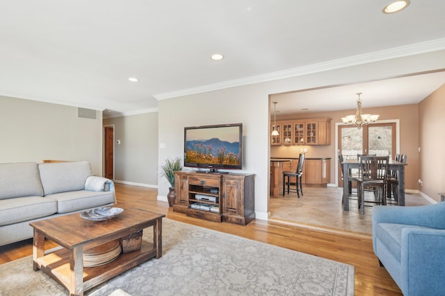 living area featuring recessed lighting, visible vents, baseboards, ornamental molding, and light wood finished floors