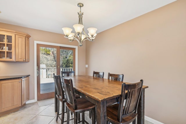 dining area featuring light tile patterned floors, baseboards, and a notable chandelier