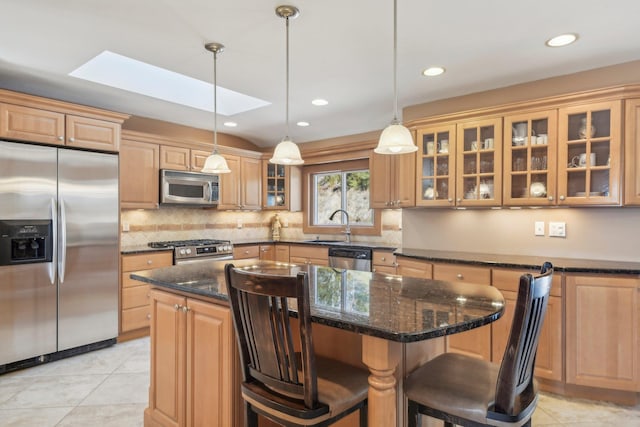 kitchen with a breakfast bar, a kitchen island, appliances with stainless steel finishes, backsplash, and glass insert cabinets