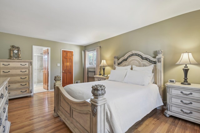 bedroom featuring ensuite bath, visible vents, and wood finished floors