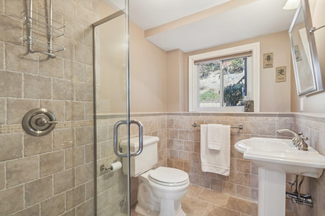 full bath featuring a stall shower, a wainscoted wall, tile walls, and toilet