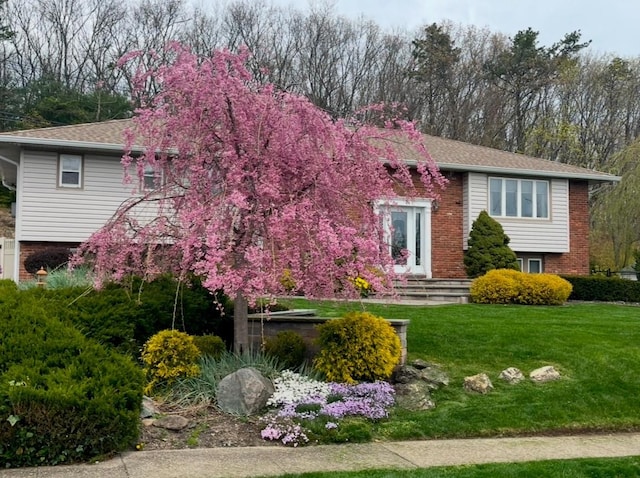 split foyer home with a front yard and brick siding