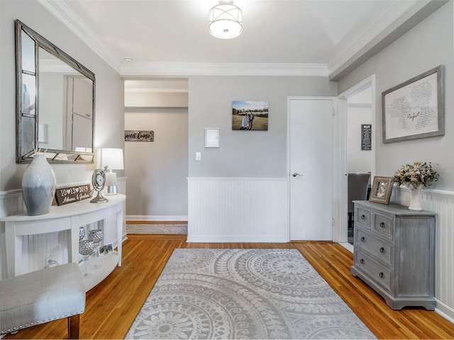interior space with a wainscoted wall, wood finished floors, and crown molding
