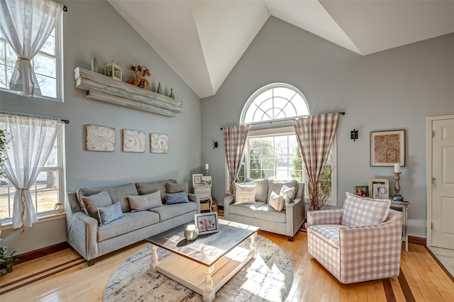 living room with high vaulted ceiling, light wood-type flooring, and baseboards