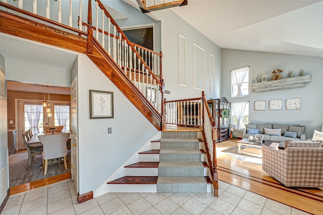 staircase featuring baseboards, high vaulted ceiling, and tile patterned floors