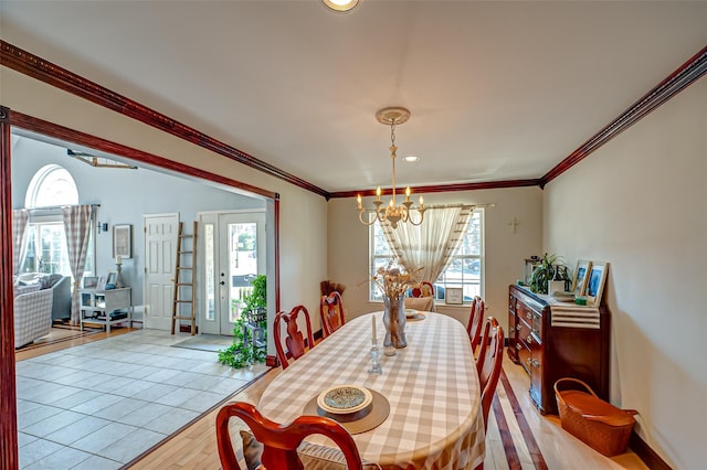 dining room featuring a chandelier, baseboards, light wood-style flooring, and crown molding