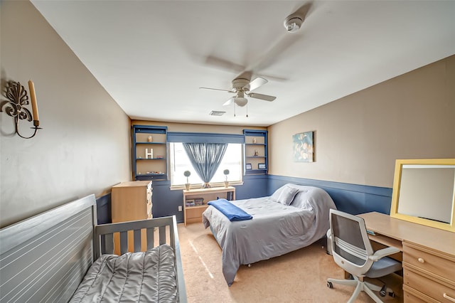 bedroom featuring a wainscoted wall, visible vents, and light colored carpet