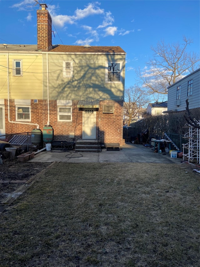 back of property featuring entry steps, fence, a yard, a patio area, and brick siding