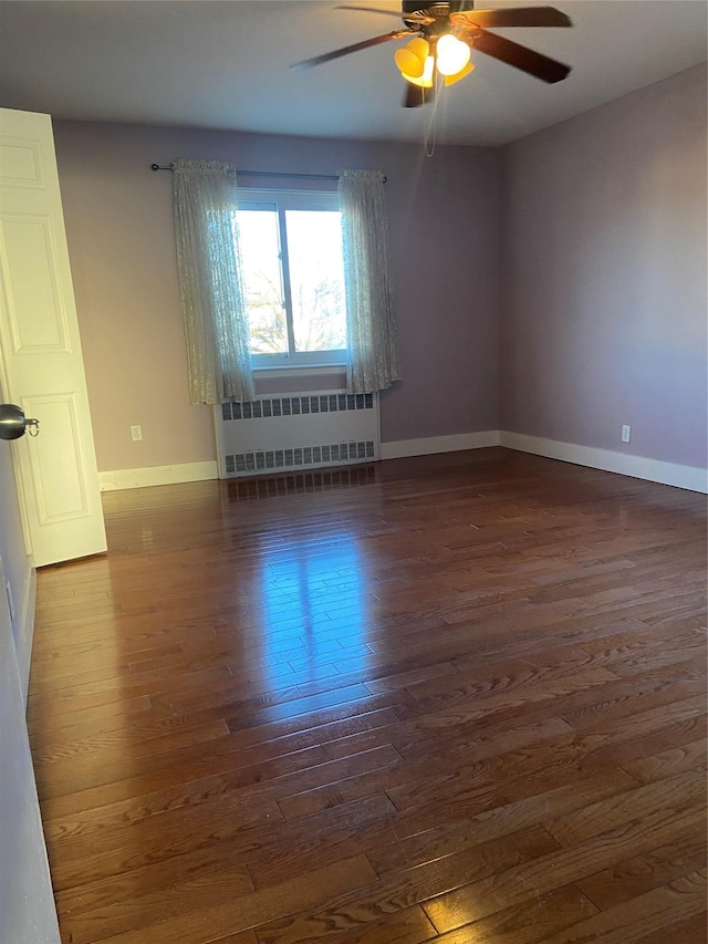 empty room with baseboards, dark wood-type flooring, a ceiling fan, and radiator