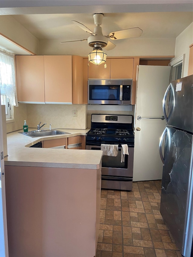 kitchen with ceiling fan, stainless steel appliances, a peninsula, a sink, and light countertops