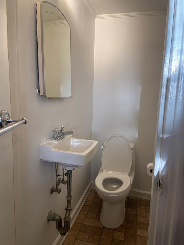 bathroom with crown molding, a sink, toilet, and baseboards