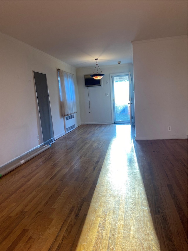 unfurnished living room with dark wood-style floors, baseboards, and radiator heating unit