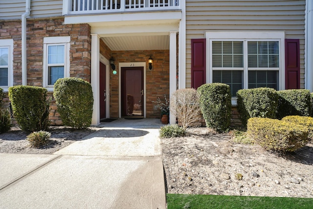 entrance to property with stone siding and a balcony