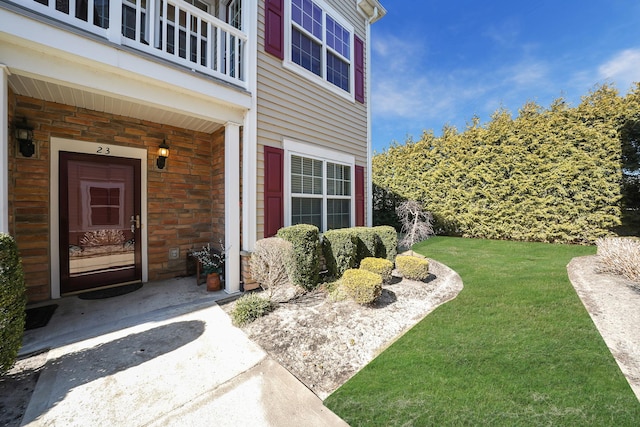 entrance to property featuring a lawn and a balcony