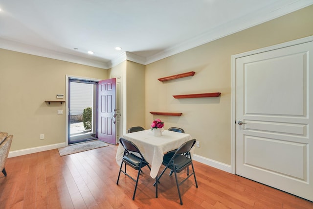 dining area with ornamental molding, light wood finished floors, and baseboards