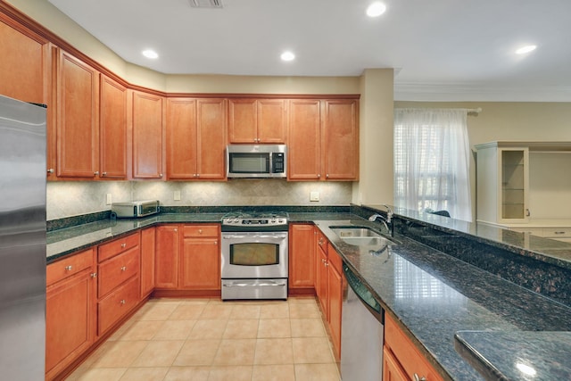 kitchen with light tile patterned floors, decorative backsplash, dark stone counters, appliances with stainless steel finishes, and a sink