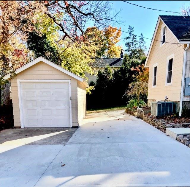 detached garage featuring driveway and central air condition unit