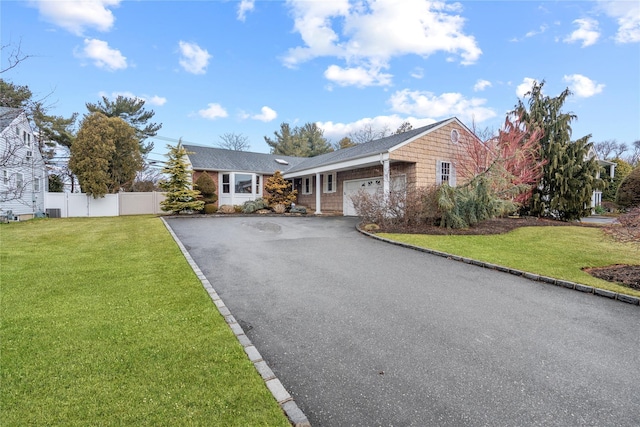 ranch-style home with a garage, driveway, a front yard, and fence