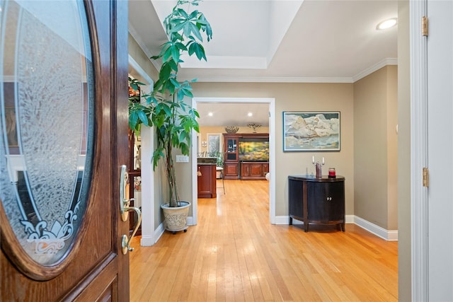 entryway with baseboards, crown molding, and light wood finished floors