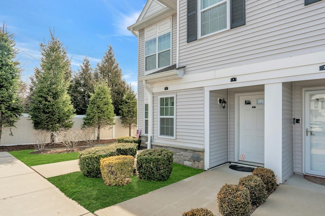 entrance to property with stone siding and fence