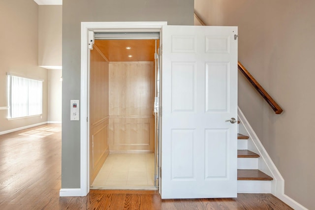 bathroom featuring elevator, baseboards, and wood finished floors