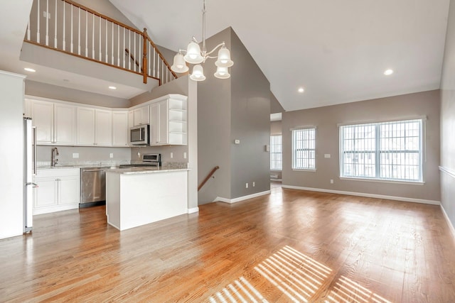 kitchen featuring open shelves, light wood-style flooring, stainless steel appliances, white cabinetry, and a sink