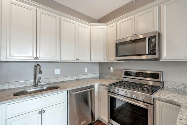 kitchen featuring a sink, light stone counters, white cabinetry, and stainless steel appliances