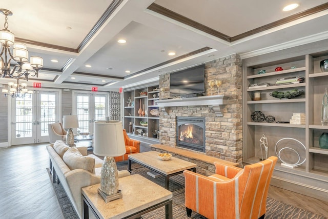 living area featuring built in features, coffered ceiling, wood finished floors, a fireplace, and a chandelier