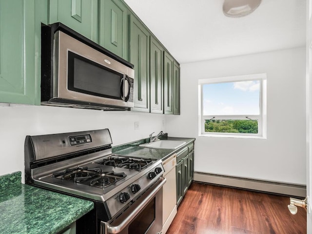 kitchen with dark countertops, a sink, stainless steel appliances, and green cabinetry