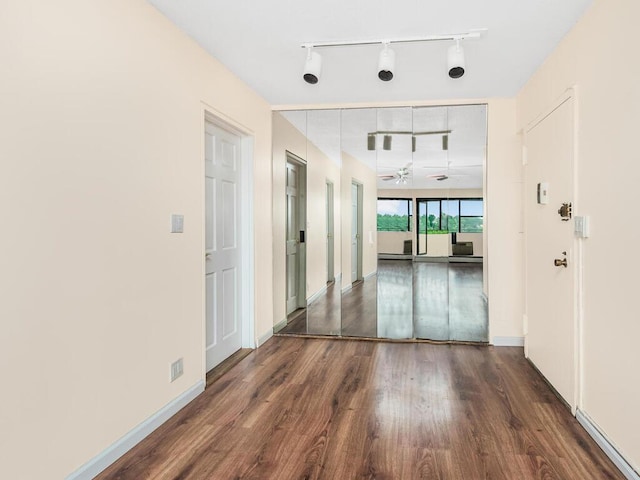 corridor with dark wood-style flooring and baseboards