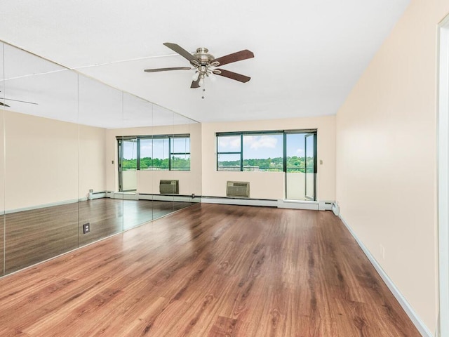 empty room with ceiling fan, a wall mounted air conditioner, wood finished floors, and baseboards