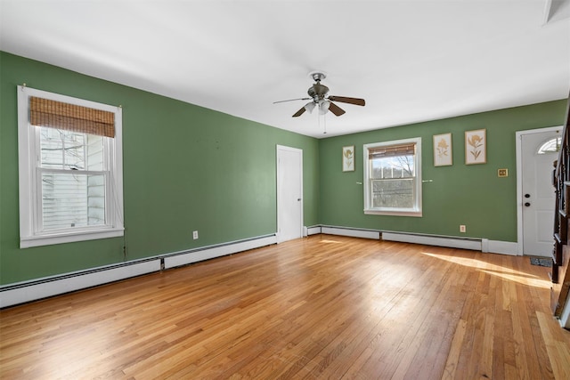 unfurnished room featuring light wood-style flooring, a baseboard radiator, and a wealth of natural light