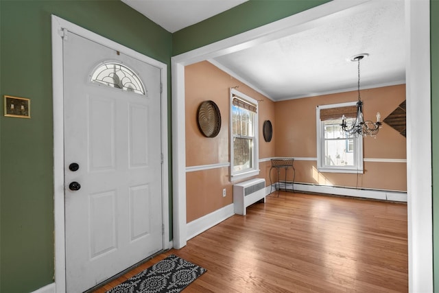 foyer entrance with a chandelier, a baseboard radiator, wood finished floors, baseboards, and radiator heating unit