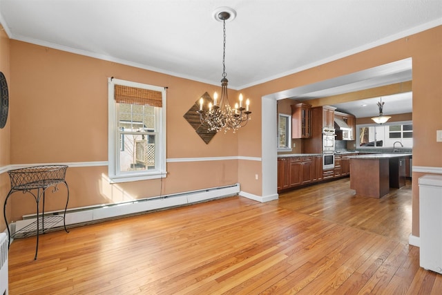 dining area with light wood-type flooring, a chandelier, baseboard heating, and crown molding