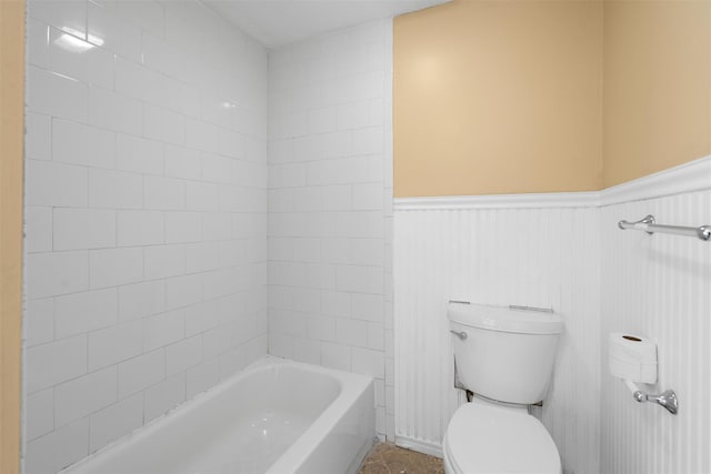 full bathroom featuring toilet, a wainscoted wall, and tub / shower combination