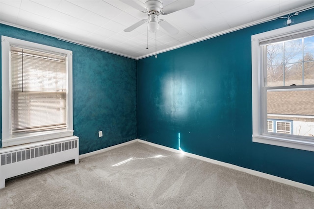 empty room with radiator, baseboards, ornamental molding, and carpet flooring