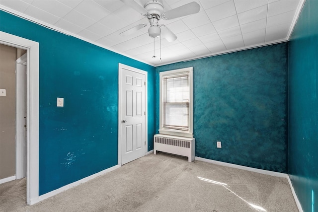 unfurnished room featuring baseboards, a ceiling fan, light colored carpet, radiator heating unit, and crown molding