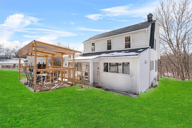 rear view of property featuring roof with shingles, a yard, a chimney, a patio, and a sunroom