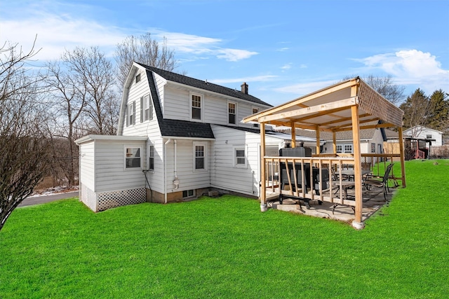 back of property featuring a shingled roof, a wooden deck, a lawn, and a gambrel roof