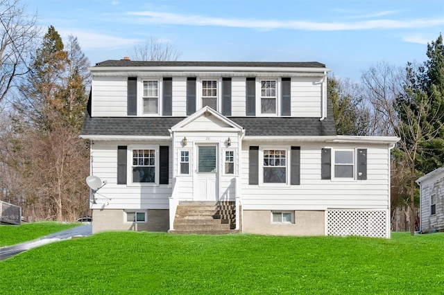 traditional-style home featuring entry steps, a front yard, and roof with shingles