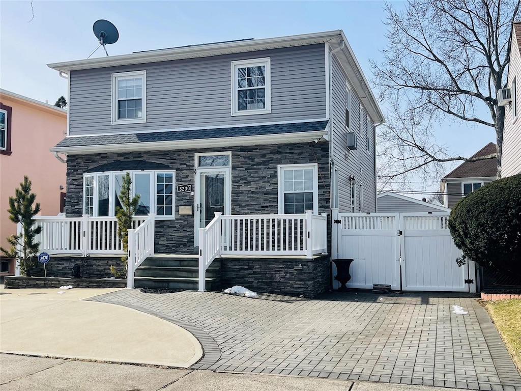 view of front of home featuring stone siding, fence, and a gate