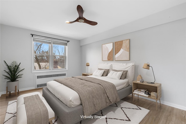 bedroom with baseboards, light wood-style floors, a ceiling fan, and radiator