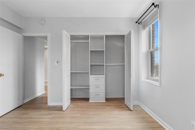 unfurnished bedroom featuring light wood-style floors, a closet, and baseboards