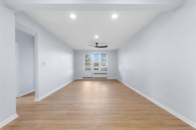 empty room with recessed lighting, a ceiling fan, baseboards, light wood finished floors, and radiator heating unit