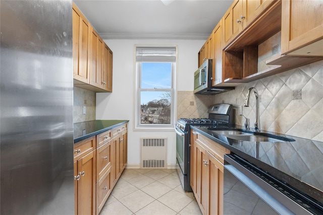 kitchen with stainless steel appliances, a sink, decorative backsplash, dark countertops, and crown molding