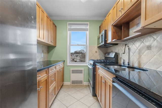 kitchen featuring dark countertops, appliances with stainless steel finishes, a sink, crown molding, and backsplash